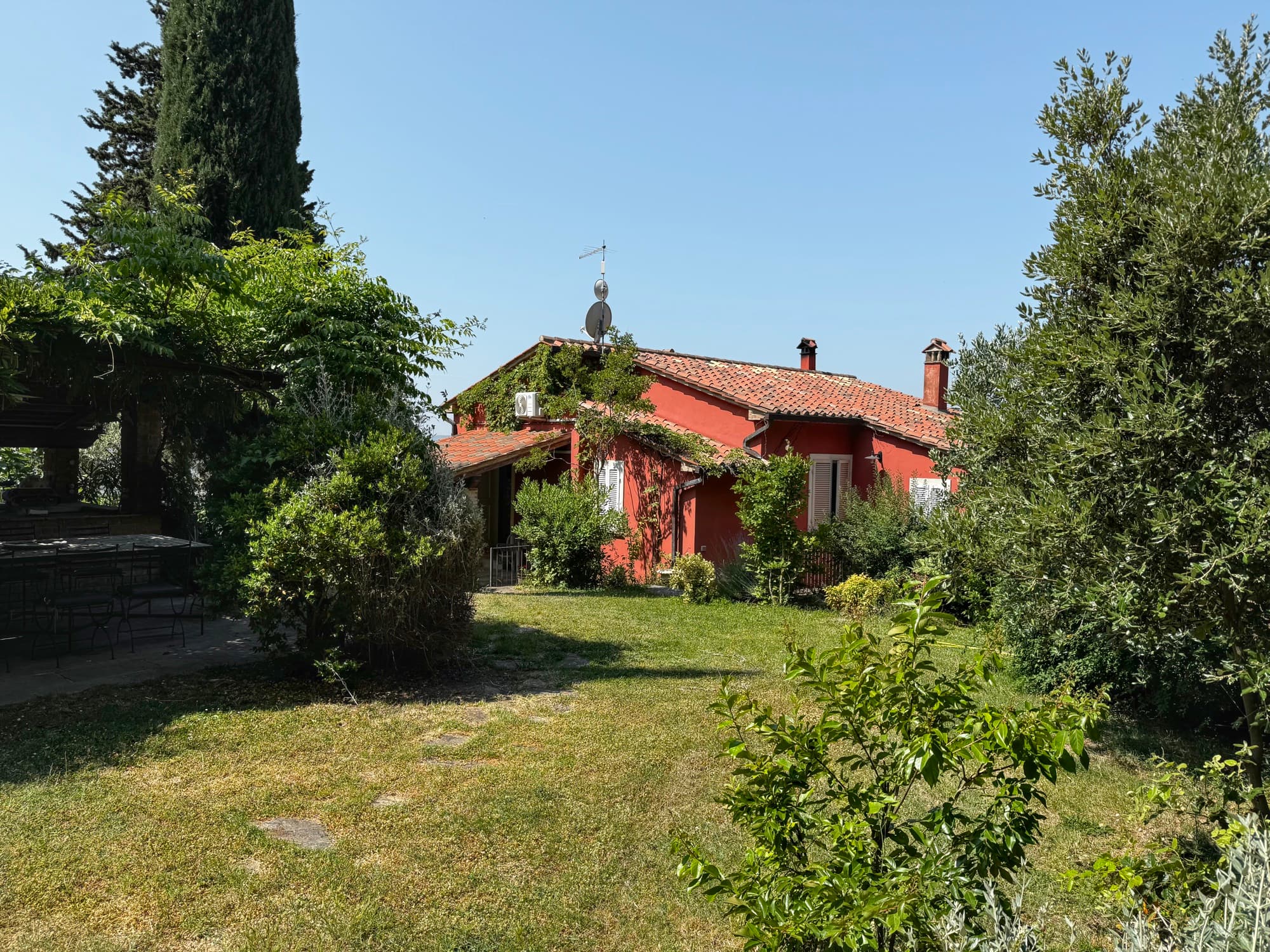 La casa vista dal prato, tra i cipressi