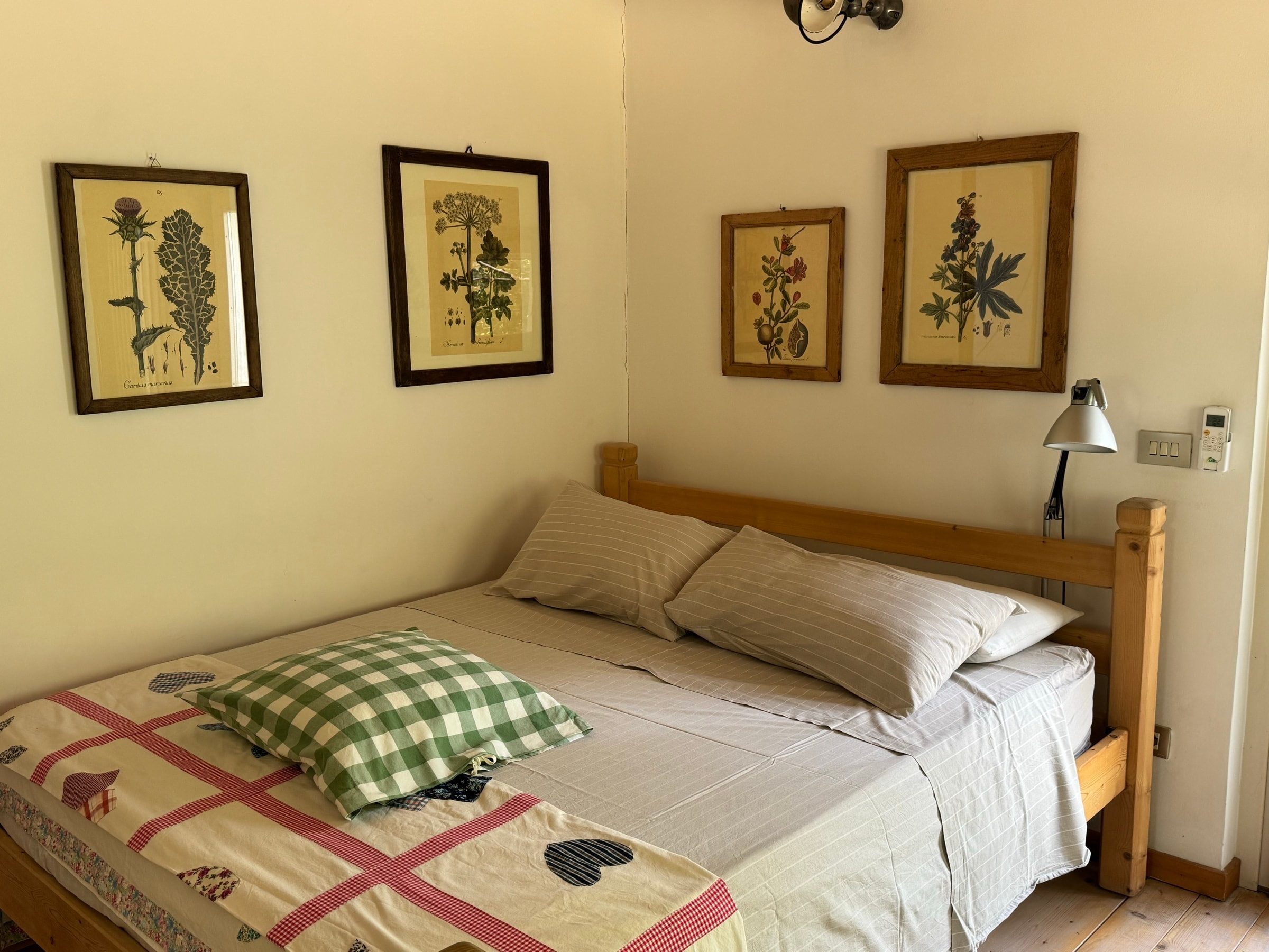 Il letto con la coperta a quadri e le stampe botaniche alle pareti
