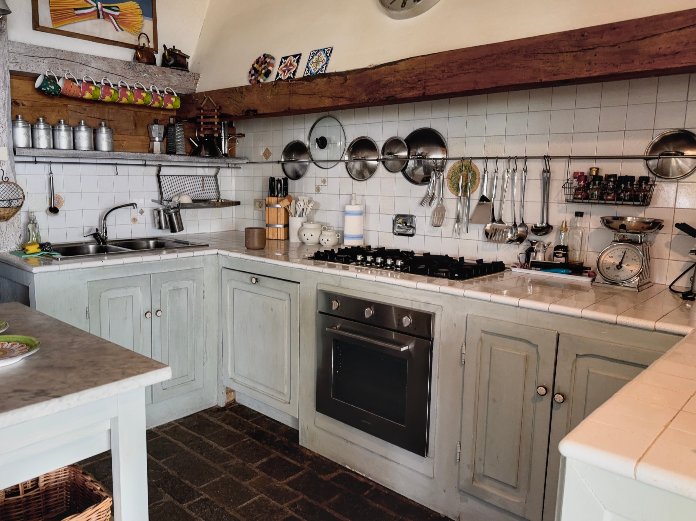 La cucina vista d’insieme, con le pentole appese e il piano cottura
