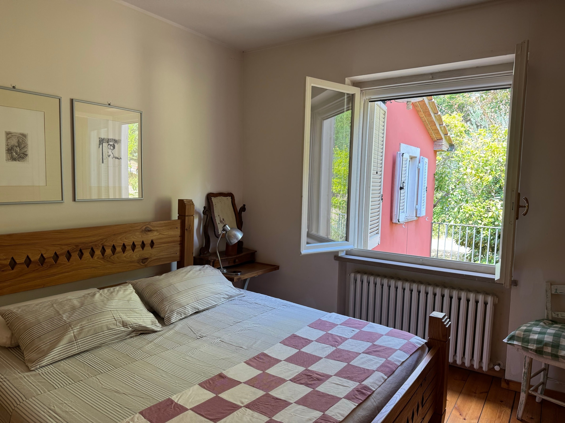 Il letto matrimoniale con le stampe alle pareti e la finestra sul verde