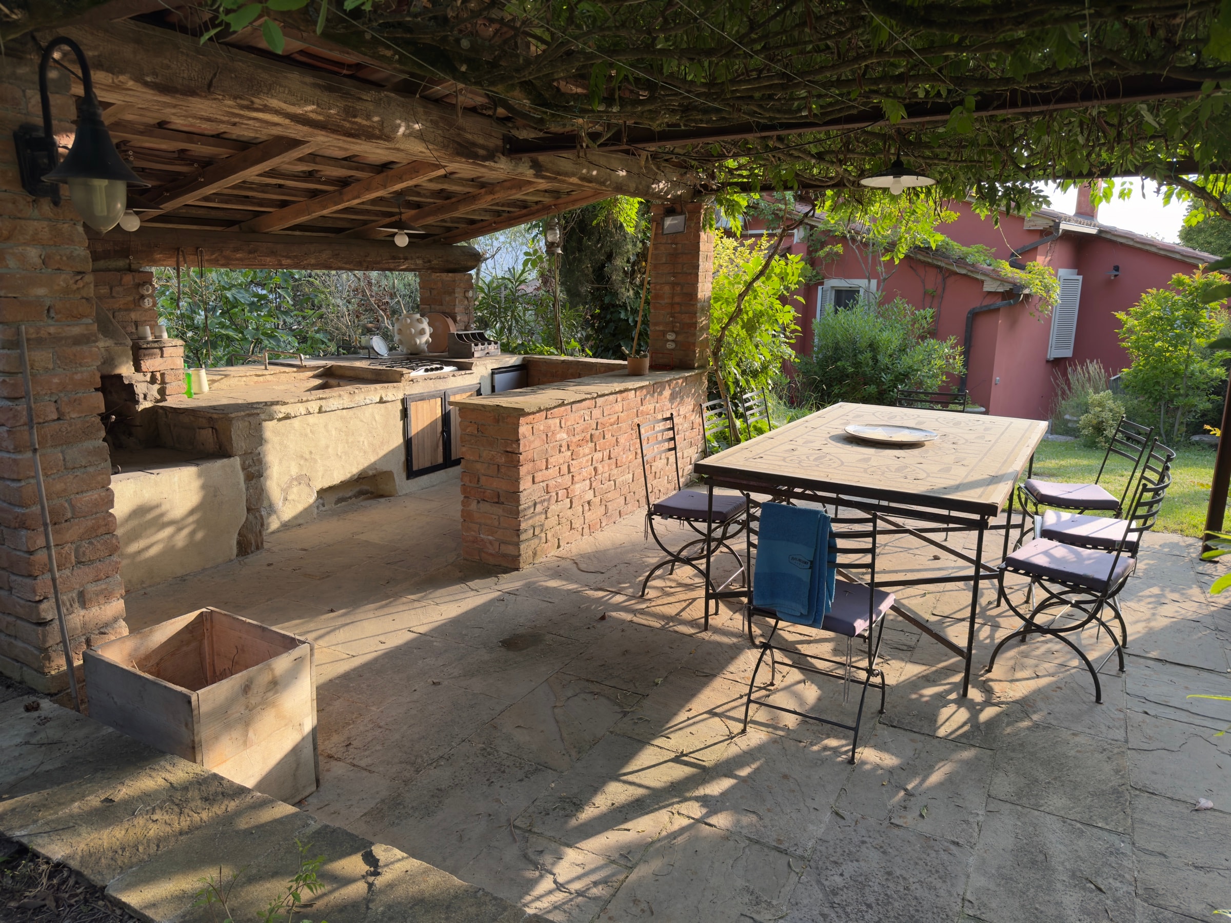 Il tavolo e le sedie sotto il pergolato, accanto alla cucina esterna